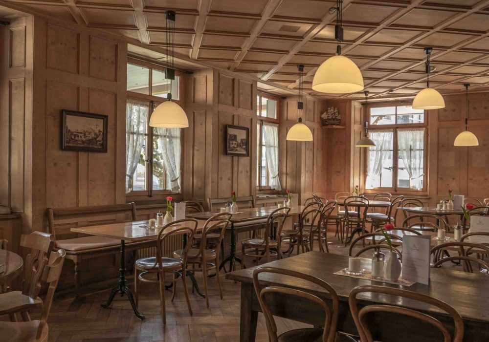 A restaurant setting with wooden chairs and tables and a beautiful view